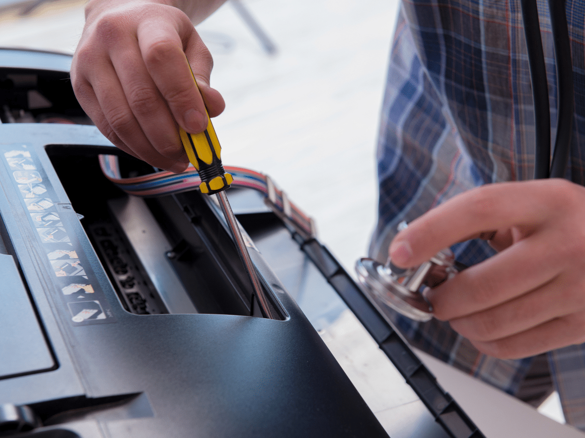 Technician performing printer repair on an office printer with tools, closeup view